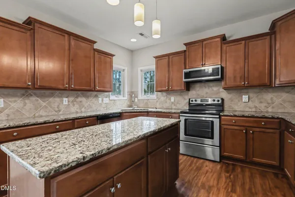a kitchen with granite countertop wooden cabinets and a stove top oven