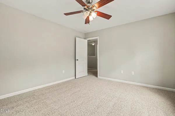 a view of an empty room and chandelier fan