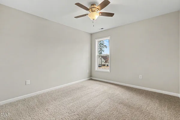 an empty room with a window and a fan