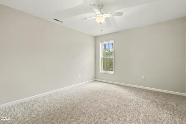 an empty room with a window and a fan