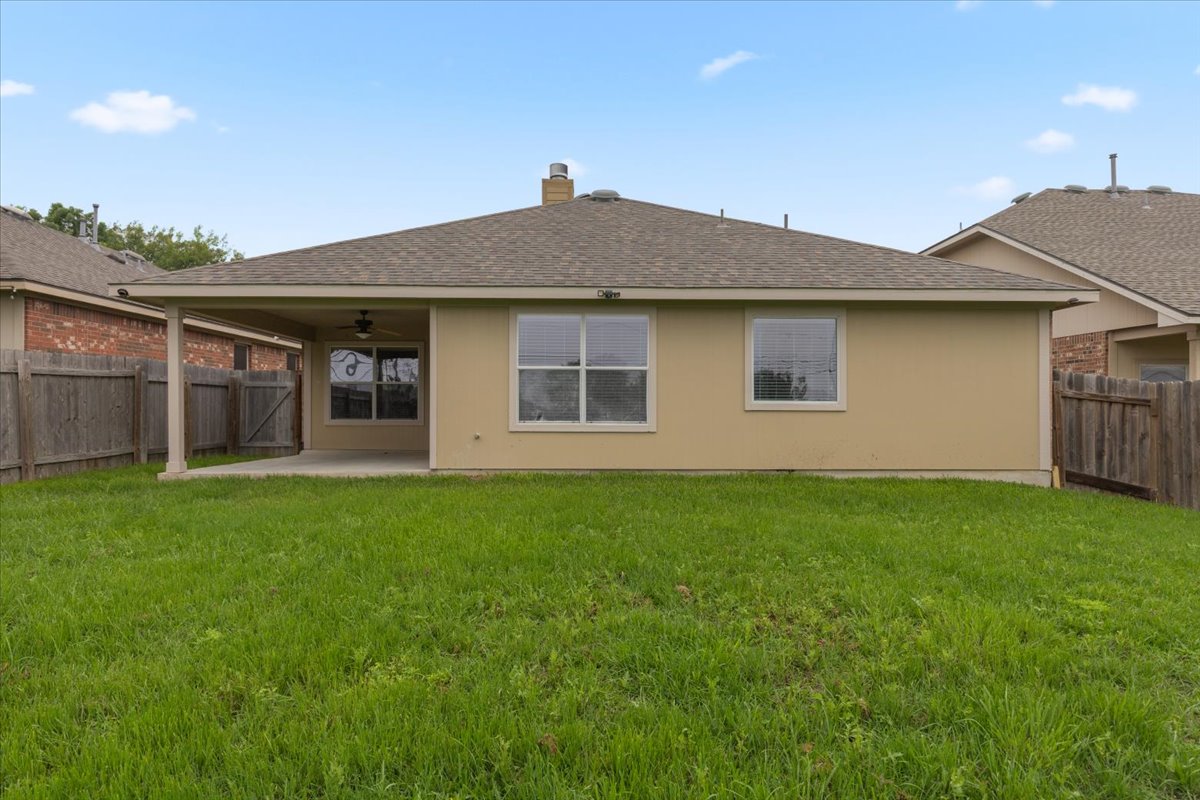 17812 Masi Loop Pflugerville, TX 78660 - Photo 33 of 38 Spacious backyard featuring a covered patio with a ceiling fan, a stucco exterior, multiple windows, and wood fencing