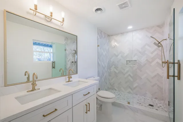 a bathroom with a shower sink vanity mirror and toilet