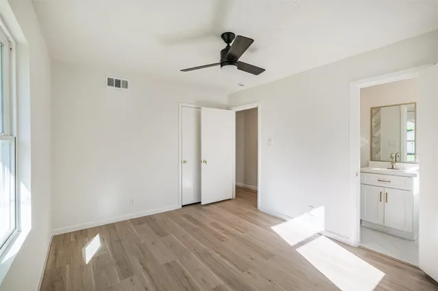 a view of empty room with wooden floor and fan