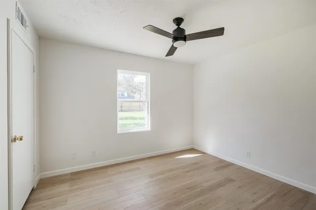 an empty room with a window and a ceiling fan