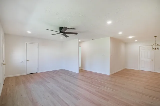 a view of an empty room with wooden floor and a ceiling fan