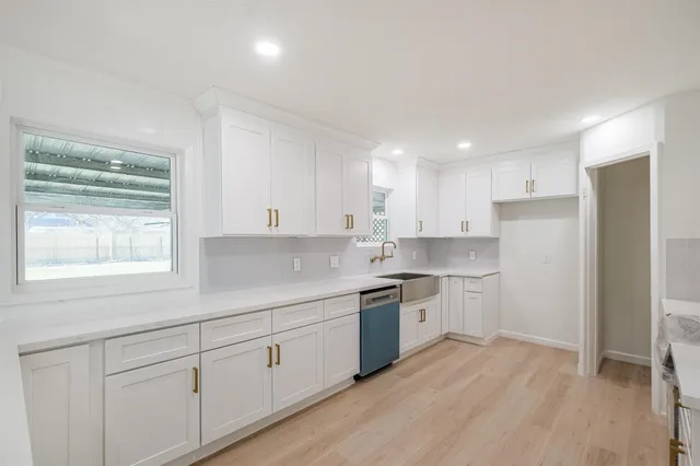 a kitchen with white cabinets appliances a sink and a window