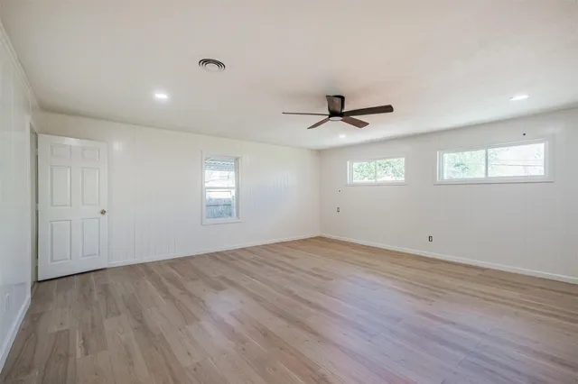 a view of empty room with wooden floor and fan