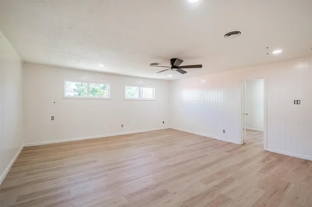 an empty room with wooden floor cabinet and windows