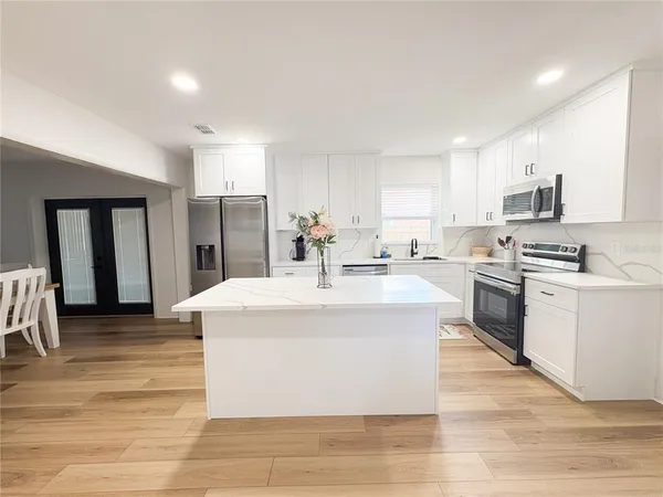 a kitchen with stainless steel appliances kitchen island a white cabinets and refrigerator