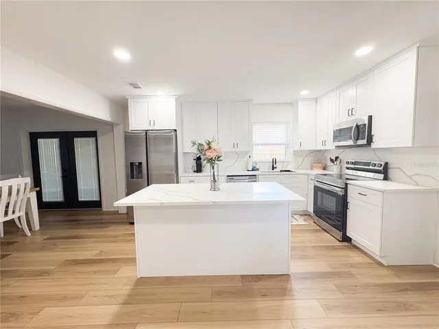 a kitchen with stainless steel appliances kitchen island a white cabinets and refrigerator