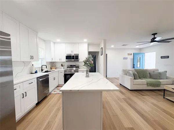 a large kitchen with stainless steel appliances kitchen island a white counter space a sink and a stove