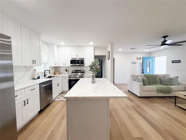 a large kitchen with stainless steel appliances kitchen island a white counter space a sink and a stove