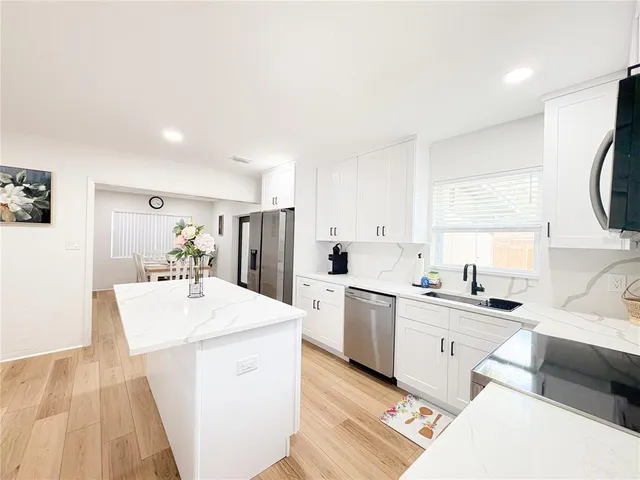 a large white kitchen with a sink a stove a refrigerator and white cabinets