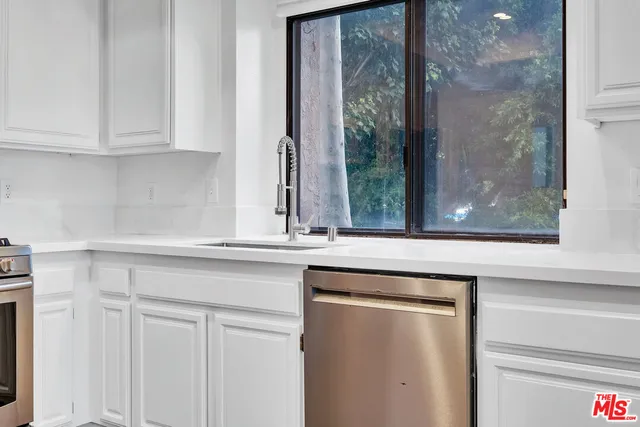 a kitchen with white cabinets and a window