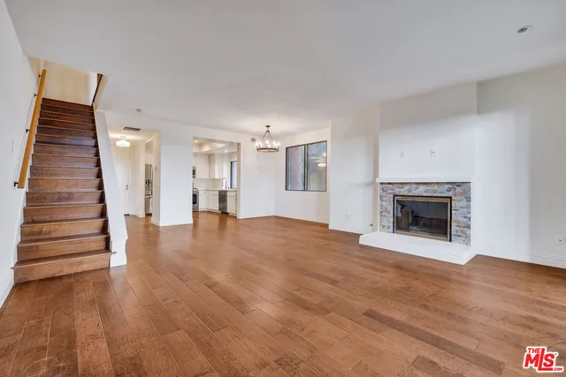 a view of an empty room with wooden floor and a fireplace