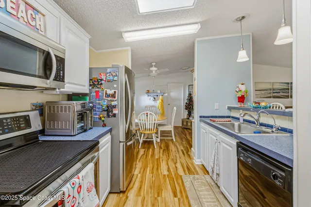 a kitchen with stainless steel appliances granite countertop a stove top oven a sink dishwasher and a dining table with wooden floor