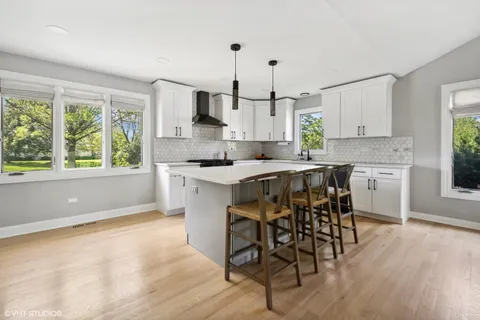 a kitchen with stainless steel appliances a white table chairs and a window