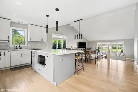 a kitchen with a stove a sink and white cabinets with wooden floor