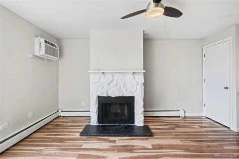 a view of an empty room with wooden floor and a fireplace
