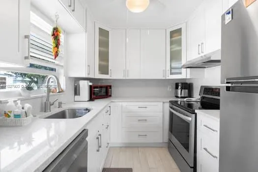a kitchen with granite countertop a sink stainless steel appliances and cabinets