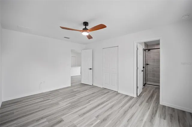 an empty room with wooden floor a ceiling fan and entryway