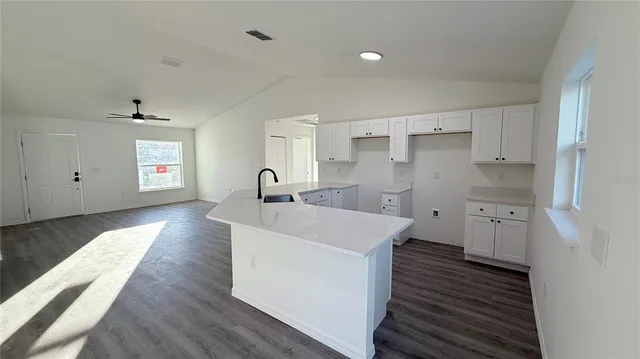 a large white kitchen with stainless steel appliances a lot of counter space and wooden floor