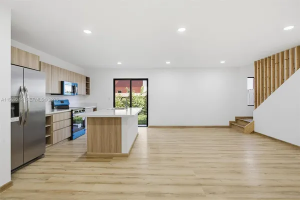 a view of a kitchen with fridge and wooden floor