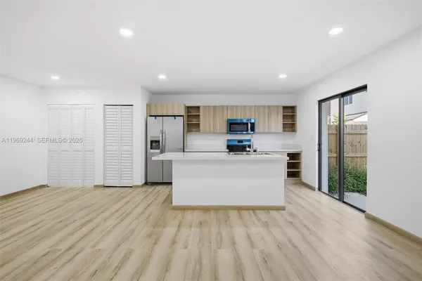 a view of kitchen with stainless steel appliances granite countertop a white stove top oven and white cabinets
