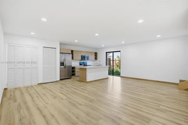 a view of a kitchen with kitchen island a sink wooden floor and a refrigerator