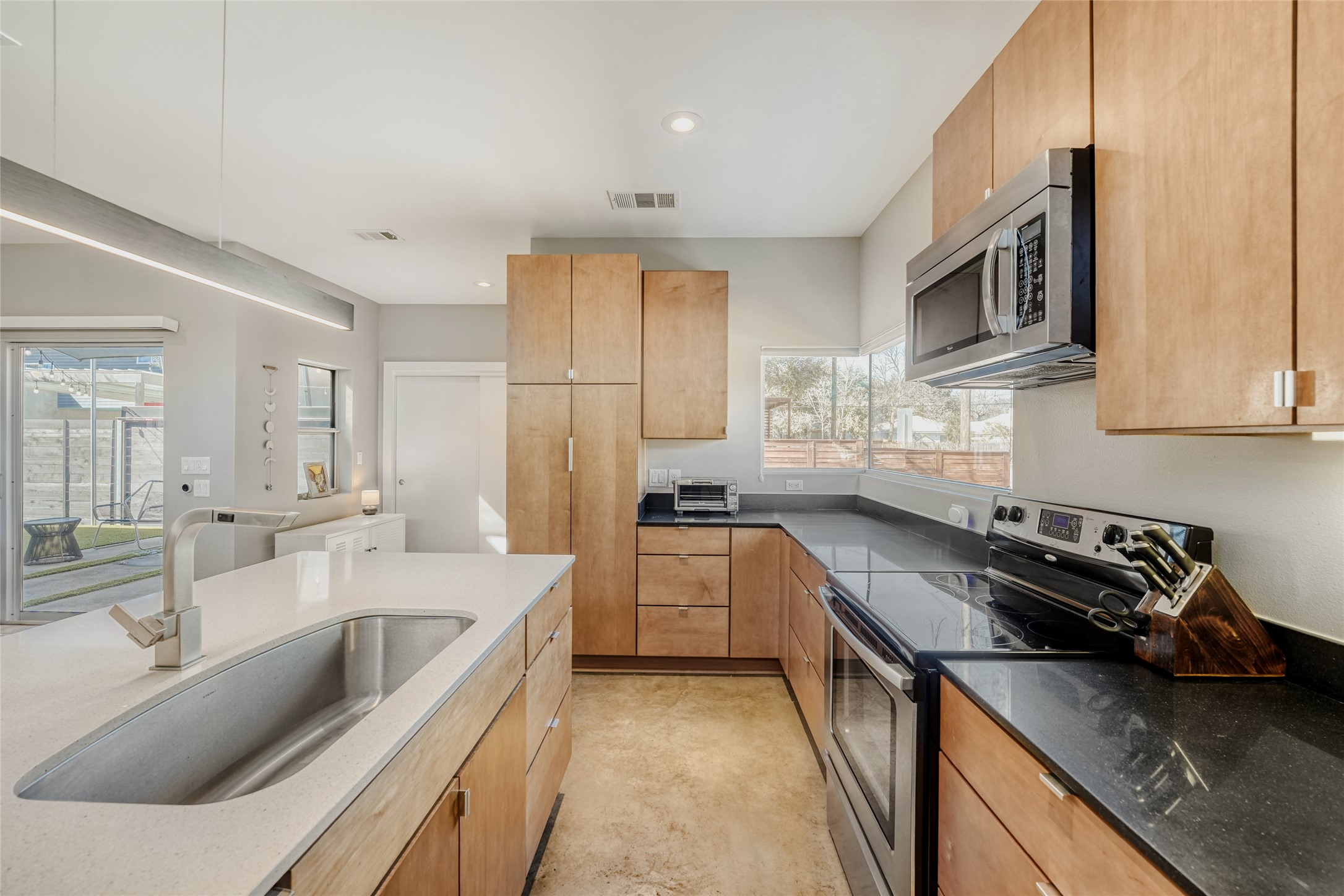5909 Lux Street Austin, TX 78721 - Photo 12 of 28 Kitchen with stainless steel appliances, dark stone counters, recessed lighting, modern cabinets, and light brown cabinetry