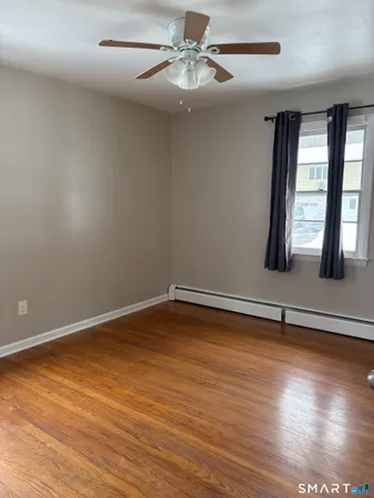 a view of an empty room with window and wooden floor