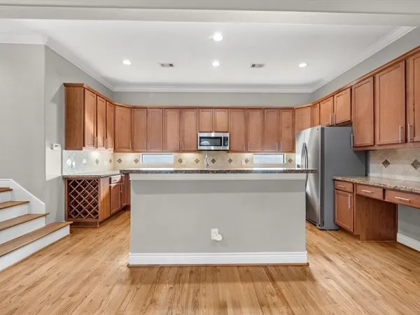 a kitchen with stainless steel appliances granite countertop a refrigerator a stove top oven a sink and dishwasher with wooden floor