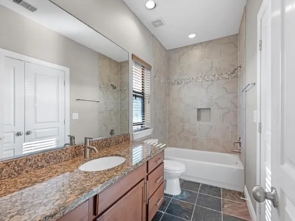 a bathroom with a granite countertop sink a mirror a bathtub and shower