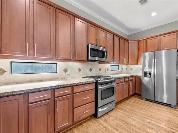 a kitchen with granite countertop wooden cabinets and stainless steel appliances