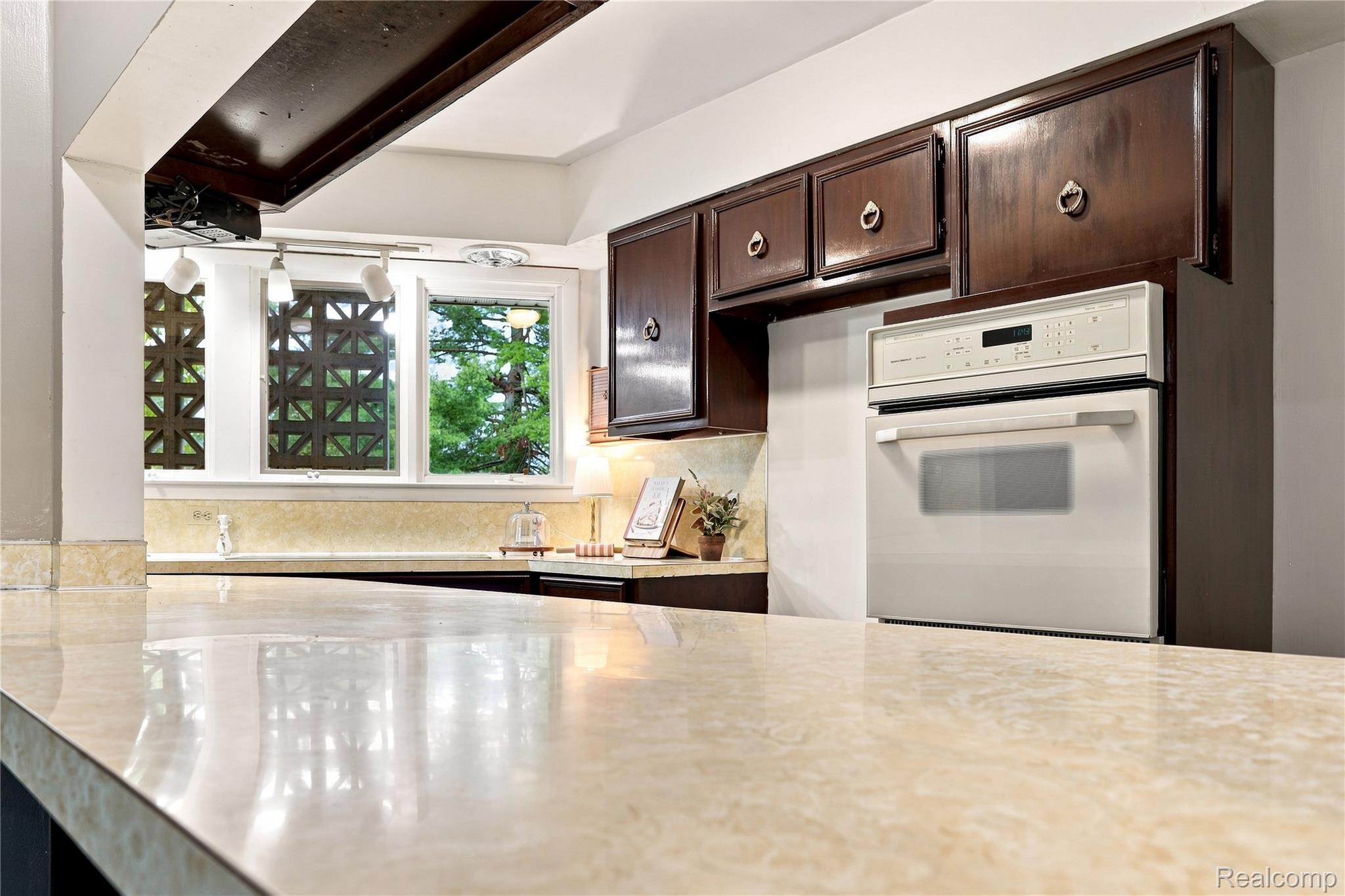 7386 Dean Road Fenton, MI 48430 - Photo 30 of 64 Kitchen featuring a built-in oven, dark wood cabinetry, and light-toned countertops