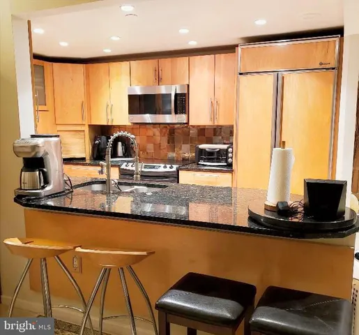 a kitchen with stainless steel appliances granite countertop a sink table and chairs