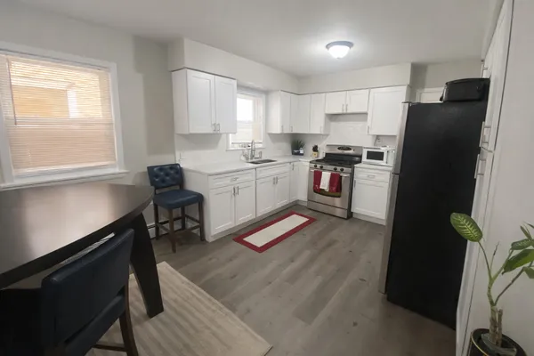 a kitchen with a refrigerator a sink dishwasher a stove and a dining table with wooden floor