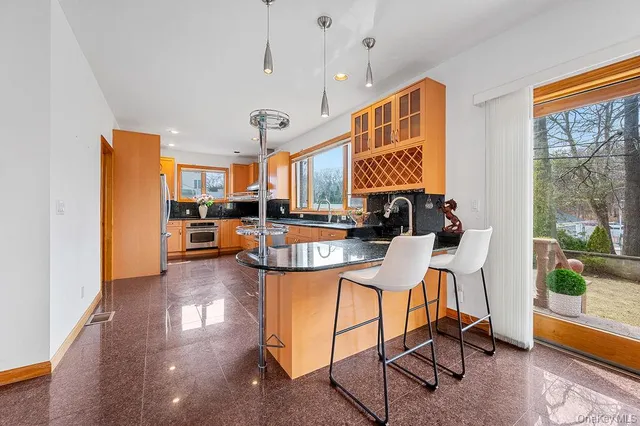 a view of a kitchen with kitchen island stainless steel appliances refrigerator stove dining table and chairs