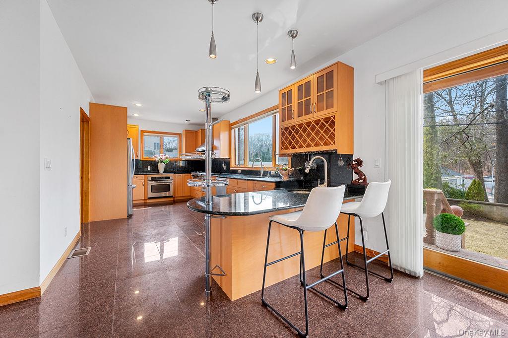 64-16 211th Street Queens, NY 11364 - Photo 6 of 22 a view of a kitchen with kitchen island stainless steel appliances refrigerator stove dining table and chairs