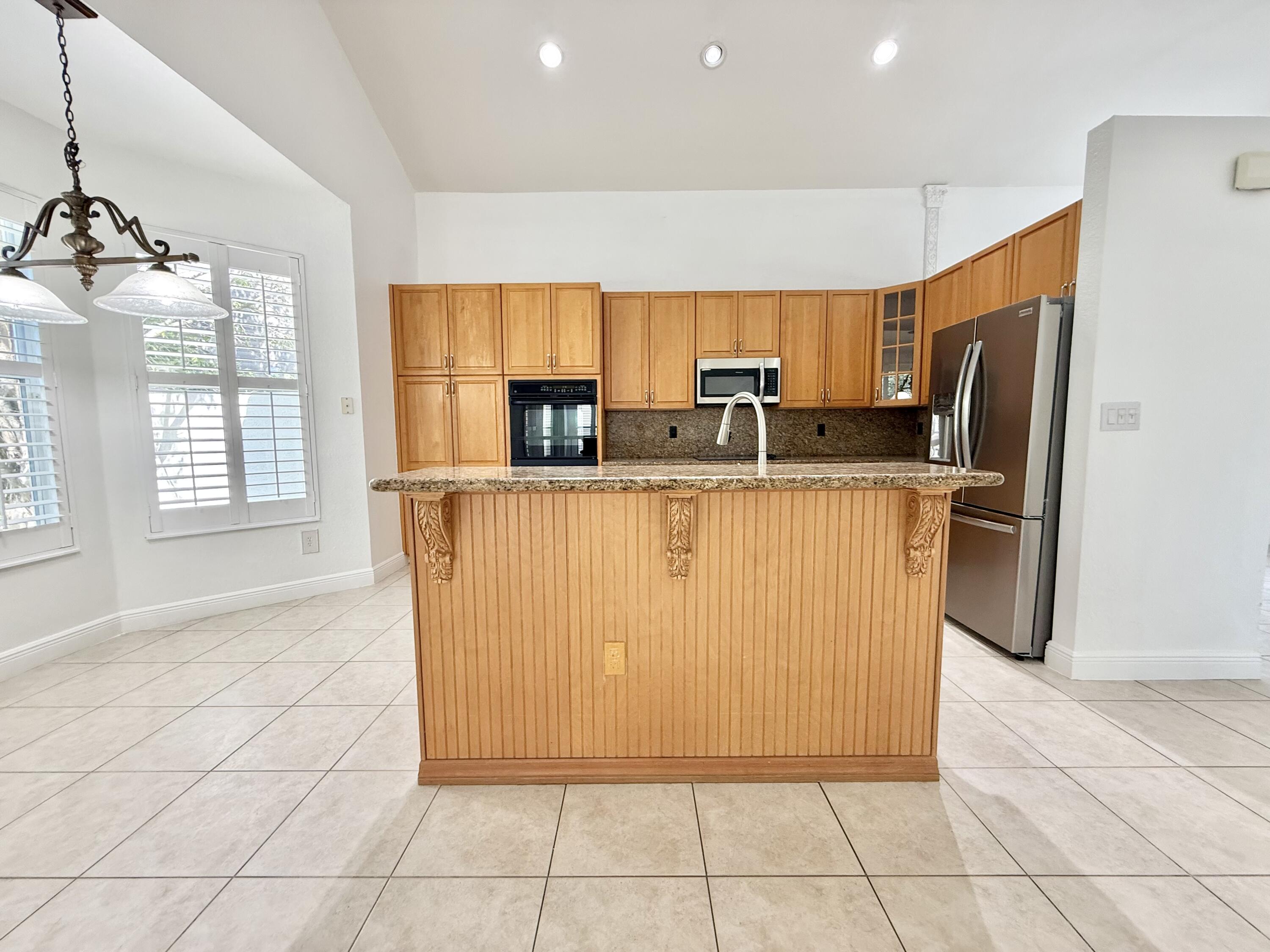 11553 Big Sky Court Boca Raton, FL 33498 - Photo 21 of 43 a kitchen with stainless steel appliances a sink a stove a refrigerator cabinets and a window