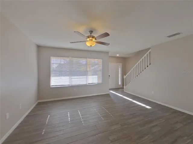 a view of an empty room with a window and wooden floor