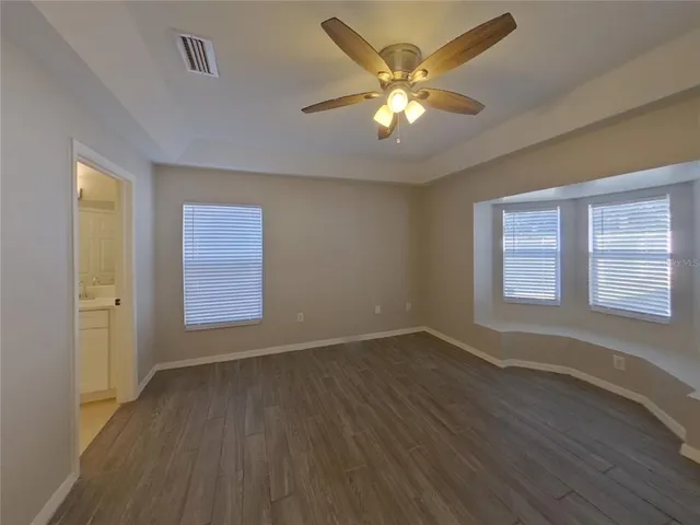 a view of an empty room with a window and wooden floor