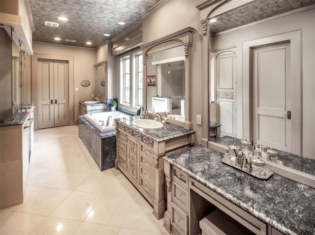 a large bathroom with a granite countertop sink a mirror and a bathtub