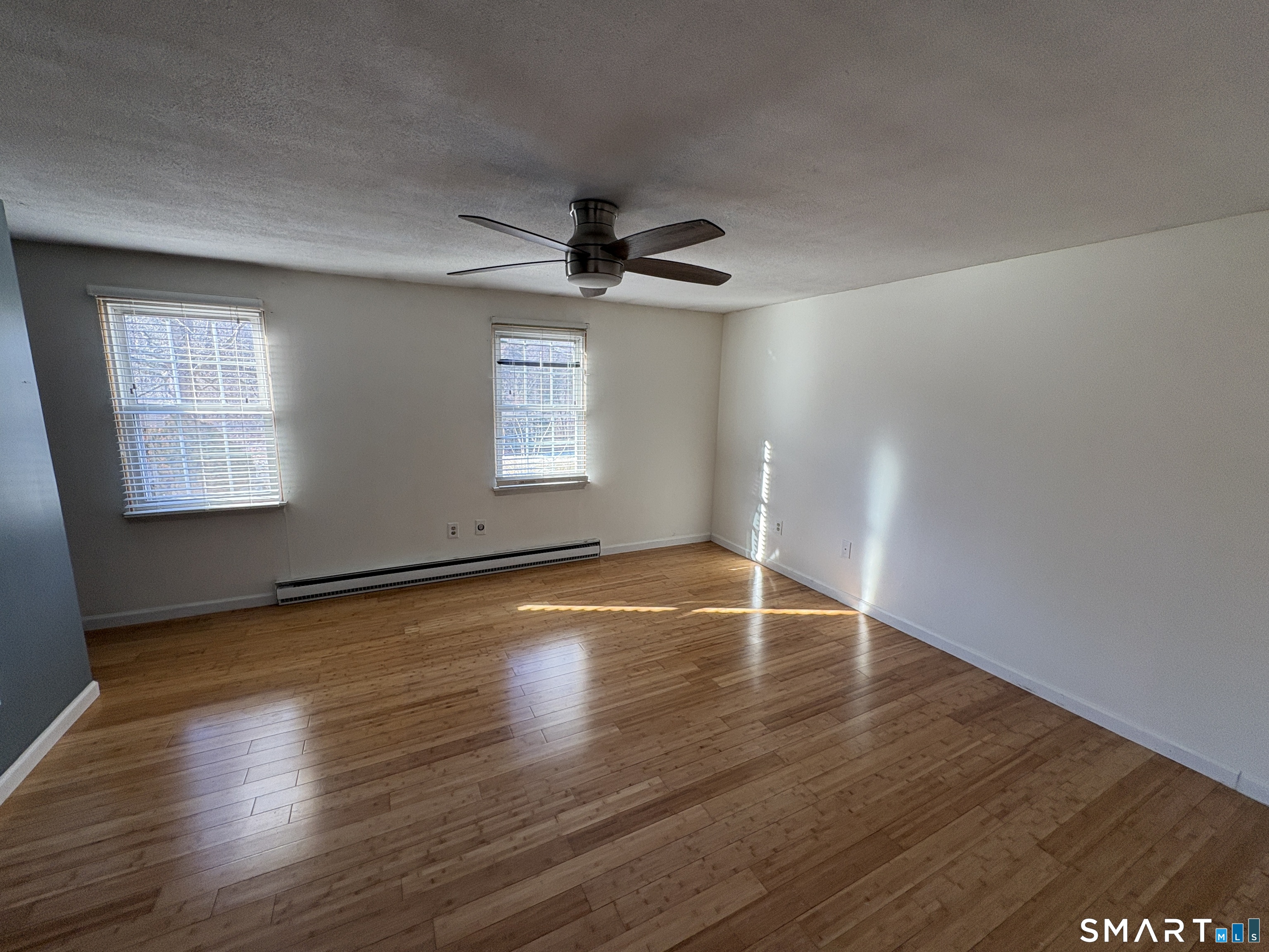 13 Lakeside Drive, Unit M Ledyard, CT 06339 - Photo 11 of 16 an empty room with wooden floor chandelier fan and windows
