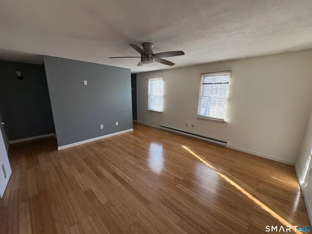 a view of empty room with wooden floor and fan