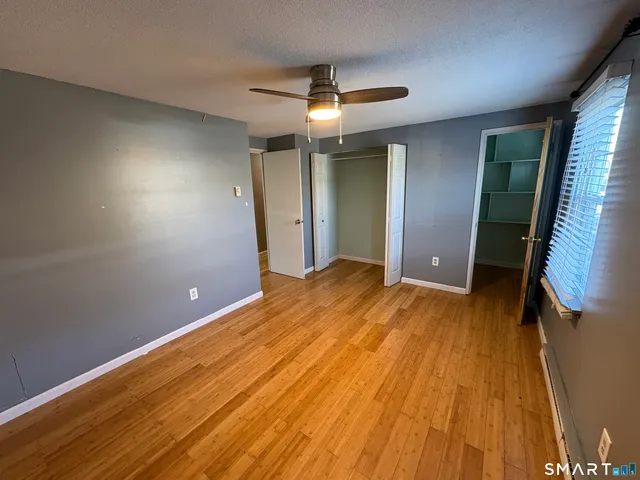 an empty room with wooden floor and a ceiling fan