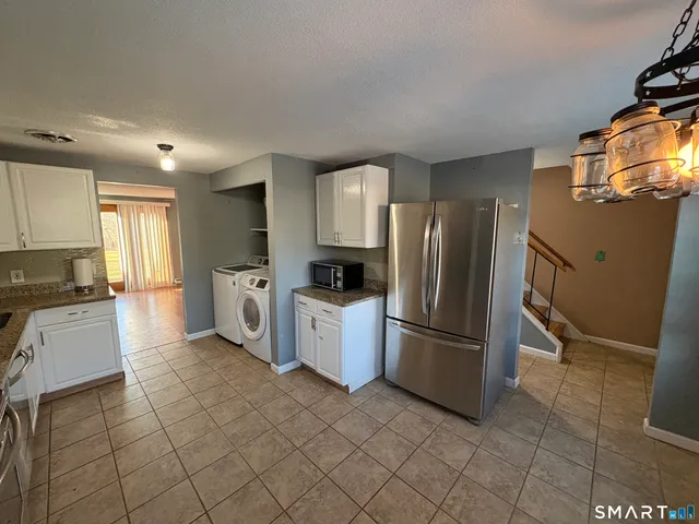 a kitchen with granite countertop a refrigerator and a stove top oven