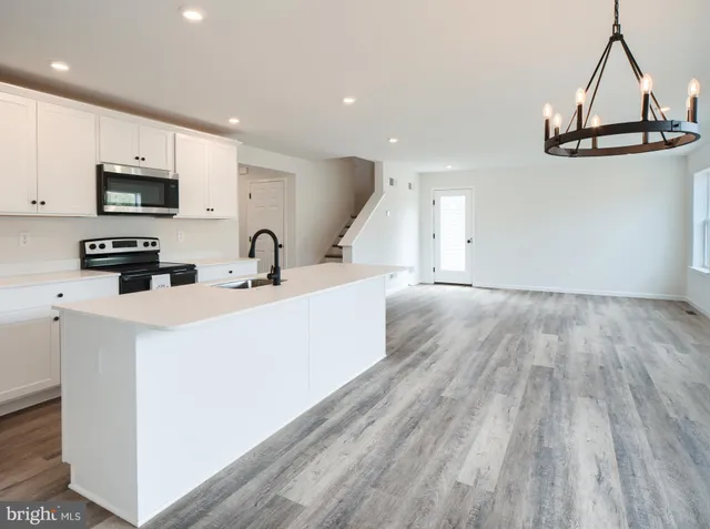 a kitchen with stainless steel appliances a sink a microwave a refrigerator and cabinets