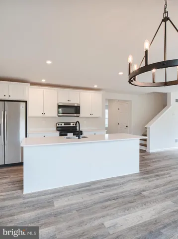 a kitchen with stainless steel appliances granite countertop a stove a refrigerator a sink and dishwasher with wooden floor