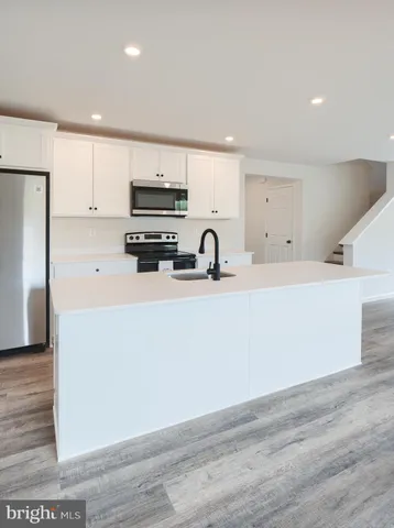 a kitchen with stainless steel appliances a sink a stove a refrigerator and cabinets